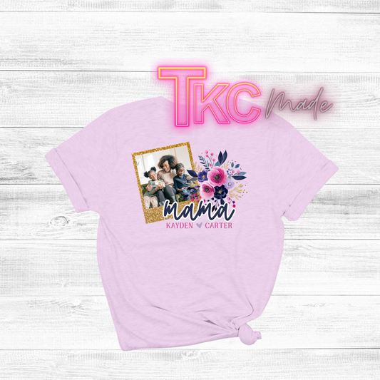 Pink t-shirt with a graphic of a family photo and floral design, on a white wooden surface.