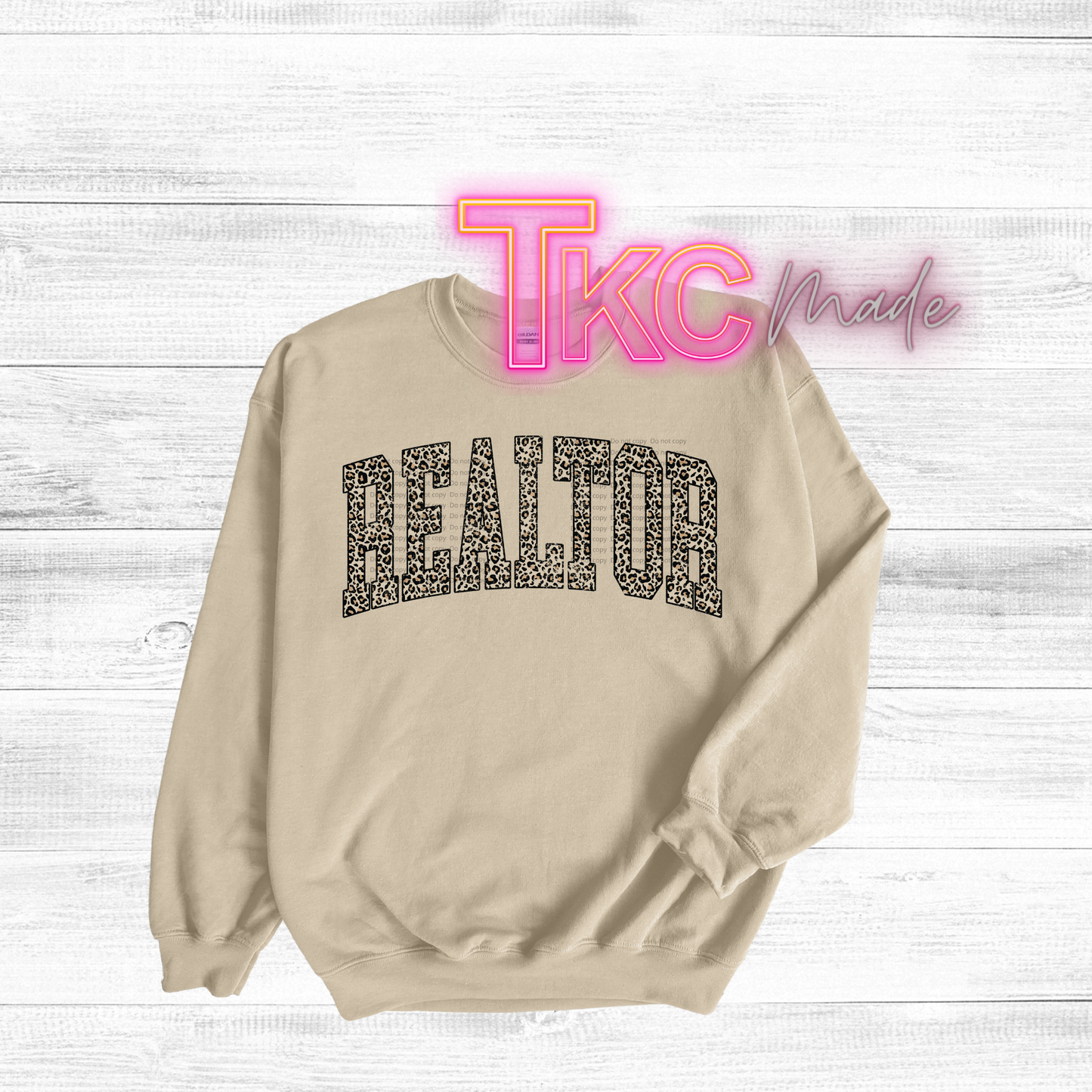 Beige sweatshirt with 'REALTOR' text on a light wood background, featuring 'TKC Made' logo.