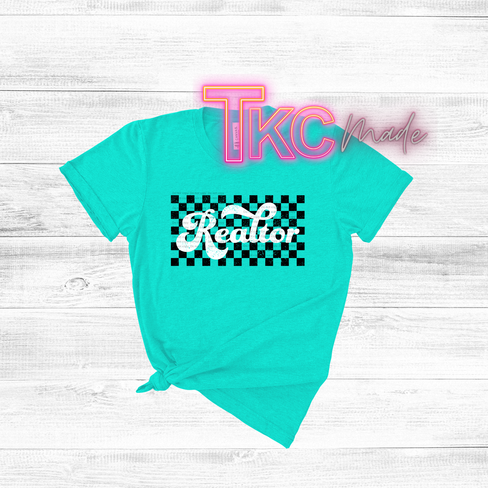Turquoise t-shirt with 'Realtor' design on a light wooden surface