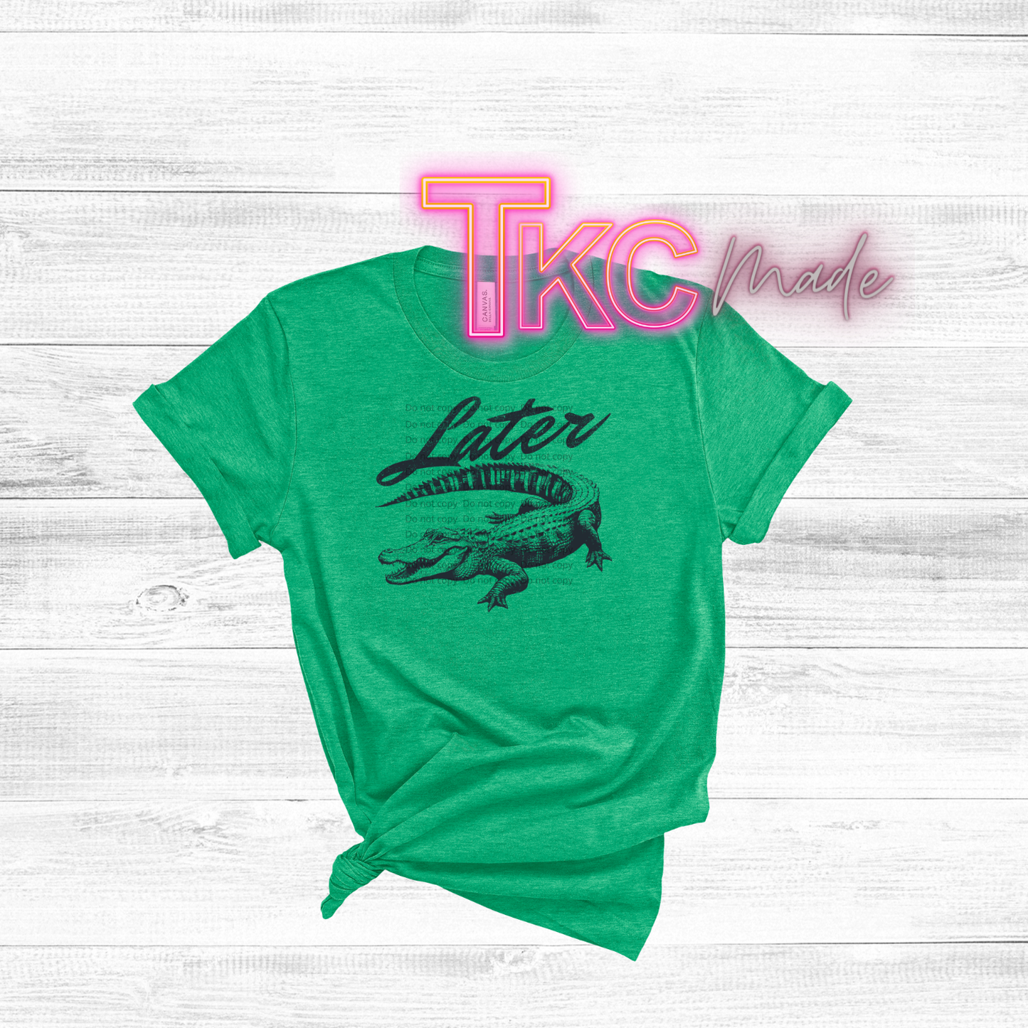 Green t-shirt with alligator graphic and 'TKC Made' text on a white wooden background