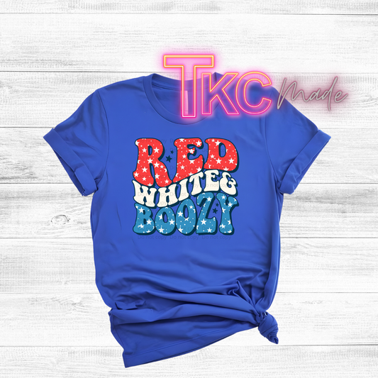 Blue t-shirt with 'Red White & Boozy' text on a wooden surface, featuring 'TKC made' branding.