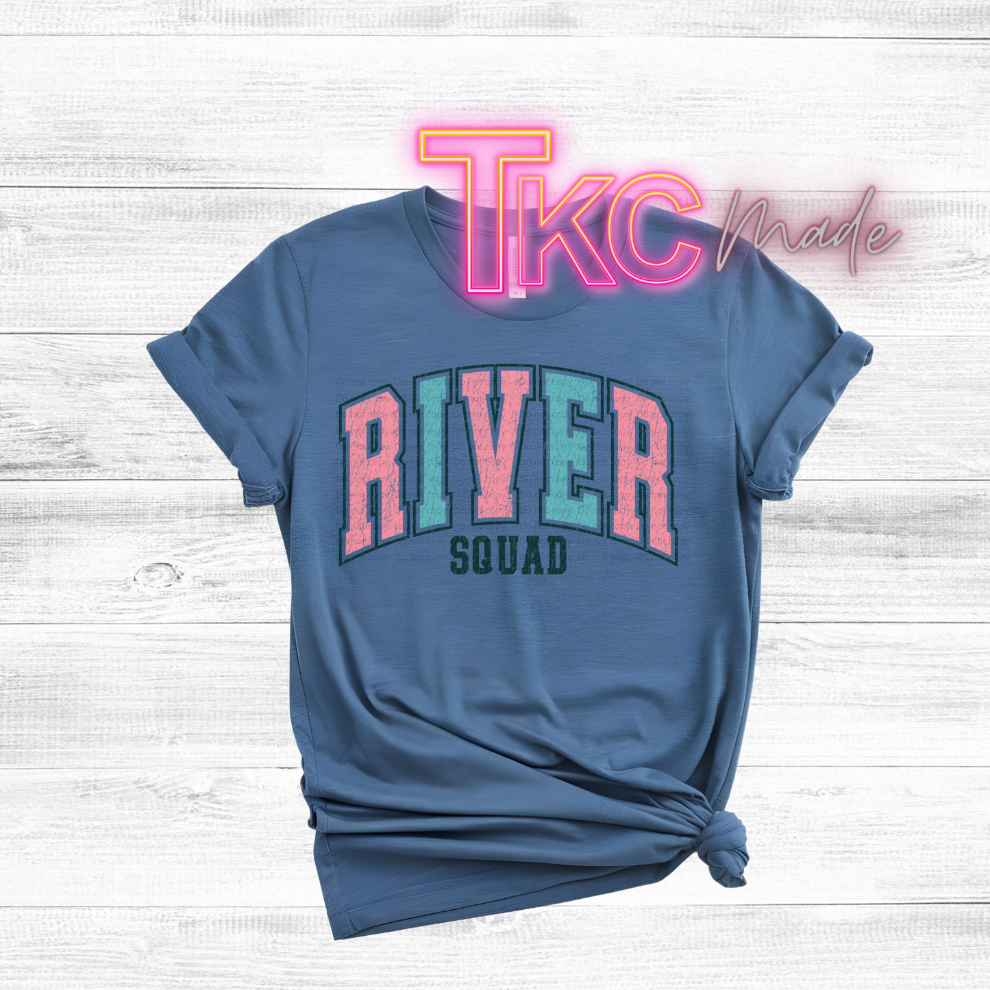Blue t-shirt with 'River Squad' text and neon 'TKC Made' on a light wooden background