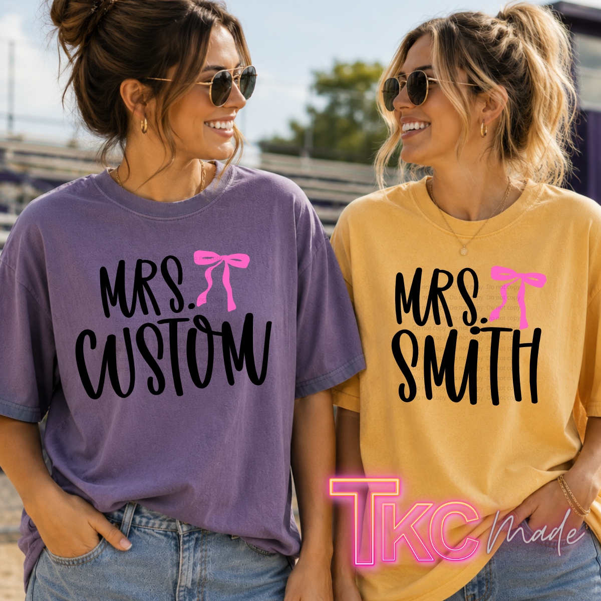 Two women outdoors wearing matching graphic t-shirts. The woman on the left wears a lavender-purple shirt with black text reading 'MRS.