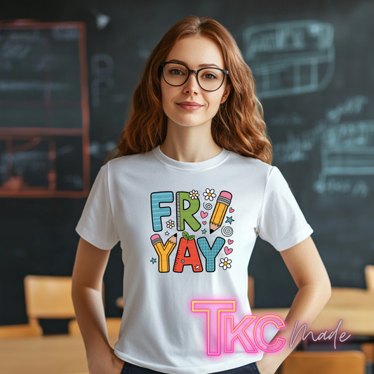 A woman with glasses and wavy light brown hair stands in a classroom setting wearing a white t-shirt with a colorful 'FRIDAY' graphic. The graphic features playful doodle-style letters in blue, green, yellow, orange, and red, decorated with small pencil, flower, and heart illustrations.