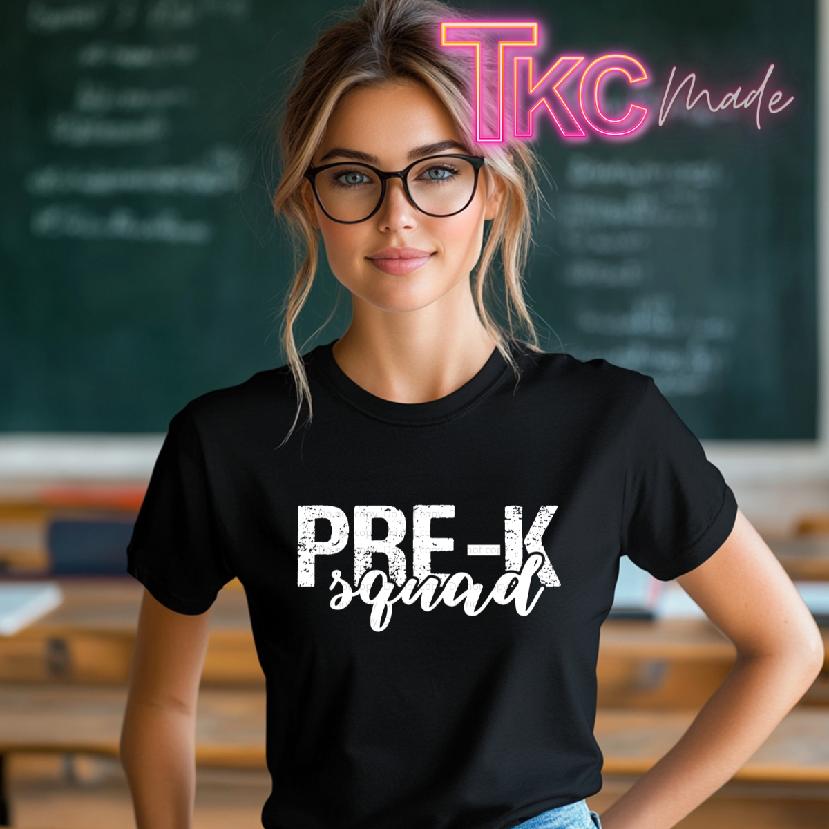 A woman wearing a black graphic t-shirt with the text 'PRE-K squad' printed in white, standing in front of a chalkboard. A pink and yellow 'TKC made' watermark is visible in the top right corner.
