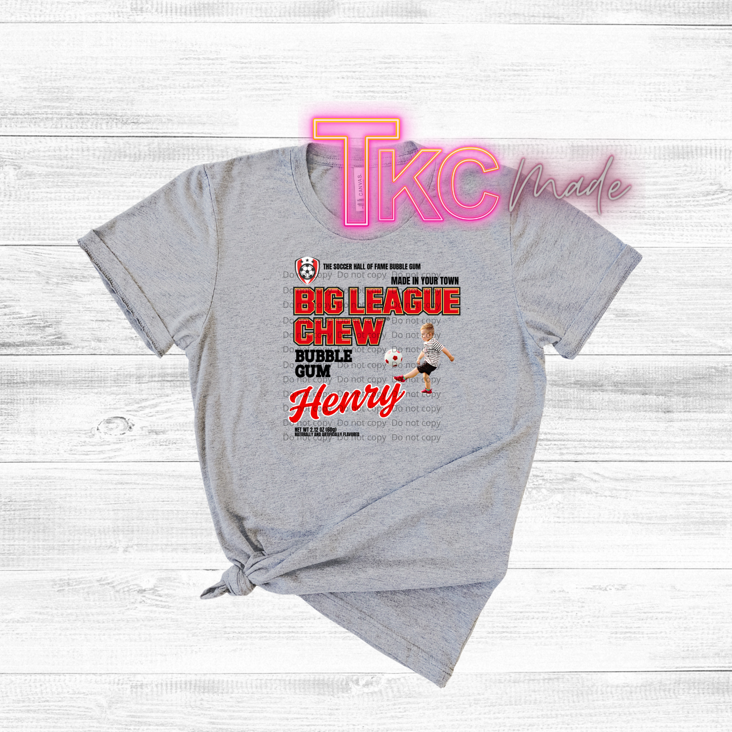 Gray t-shirt with soccer graphic and 'TKC made' branding on a light wooden background