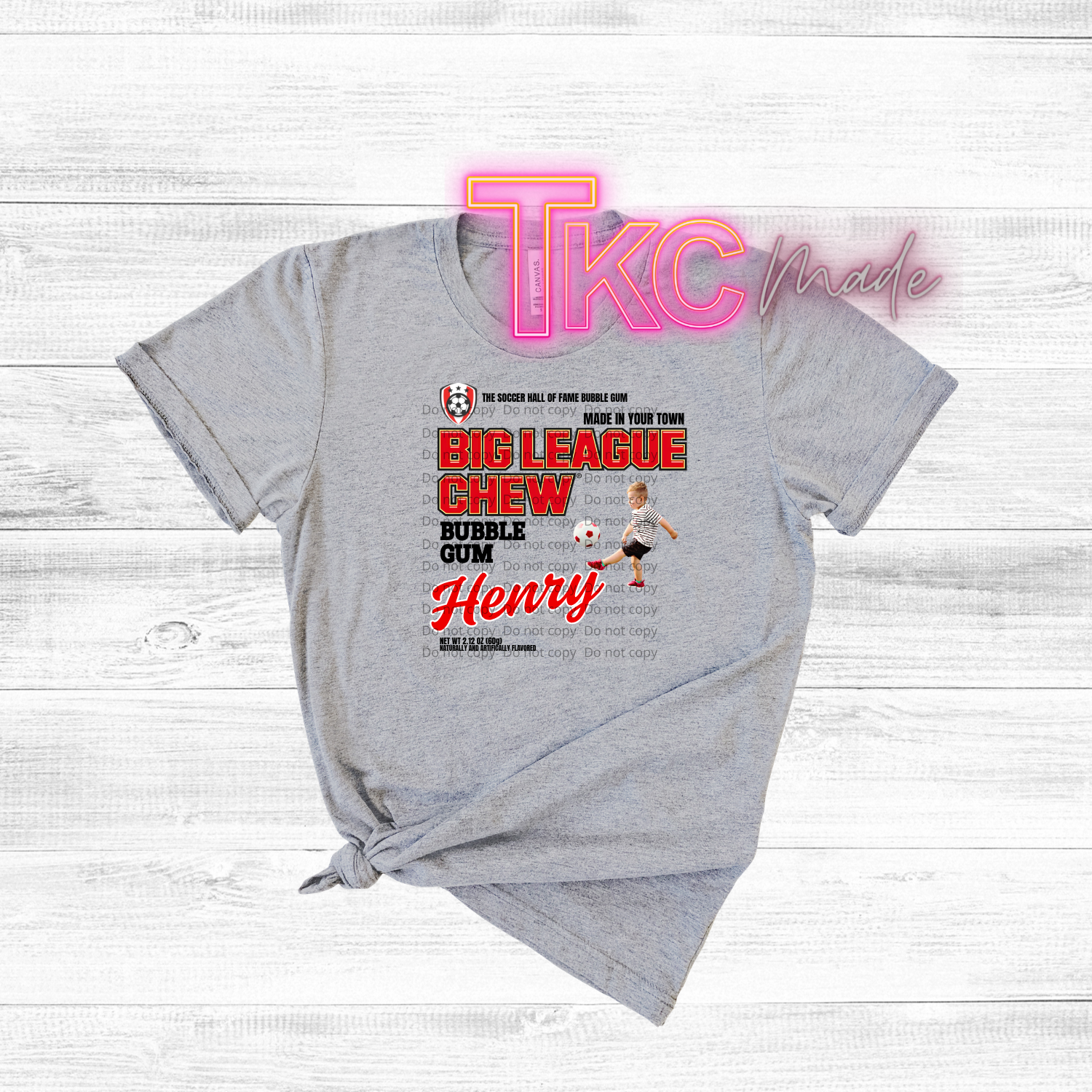 Gray t-shirt with soccer graphic and 'TKC made' branding on a light wooden background