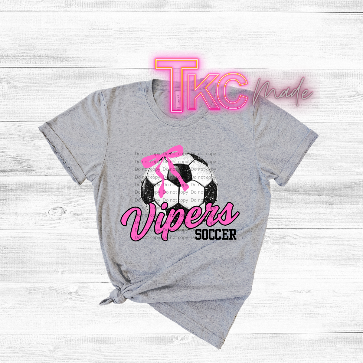 Gray t-shirt with soccer ball design and 'TKC made' text on a light wooden background