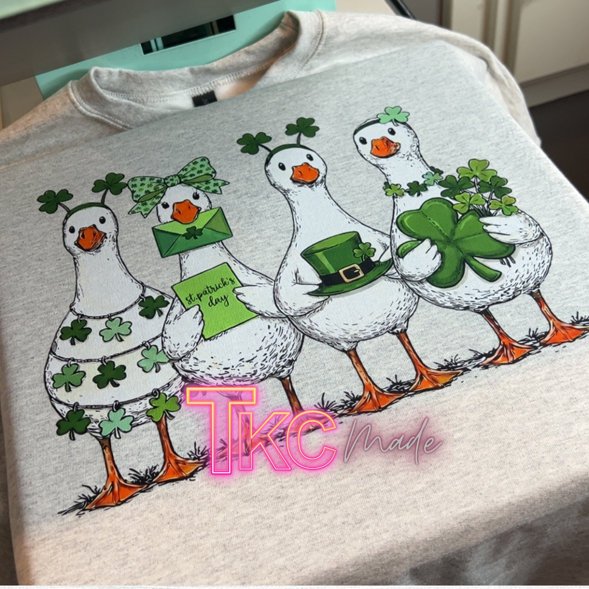 Gray sweatshirt with cartoon geese design and 'TKC made' branding.