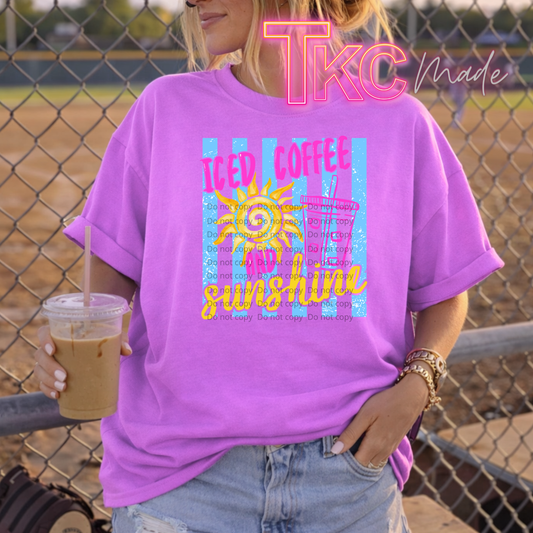 Person wearing a purple t-shirt with a graphic design and holding a drink, standing in front of a chain-link fence.