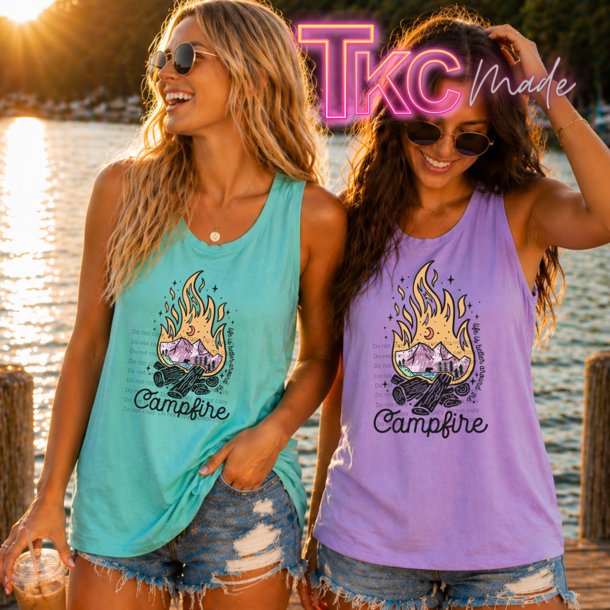 Two women wearing 'Campfire' tank tops by a body of water with 'TKC Made' neon sign.