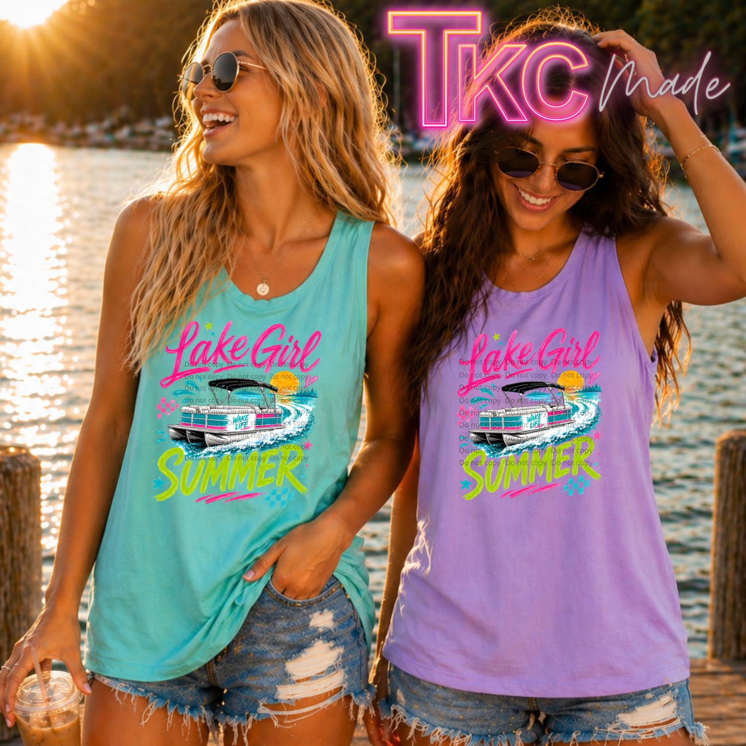 Two women wearing 'Lake Girl Summer' tank tops by a lake.