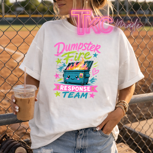 Person wearing a white t-shirt with colorful graphic design and text, holding a drink.