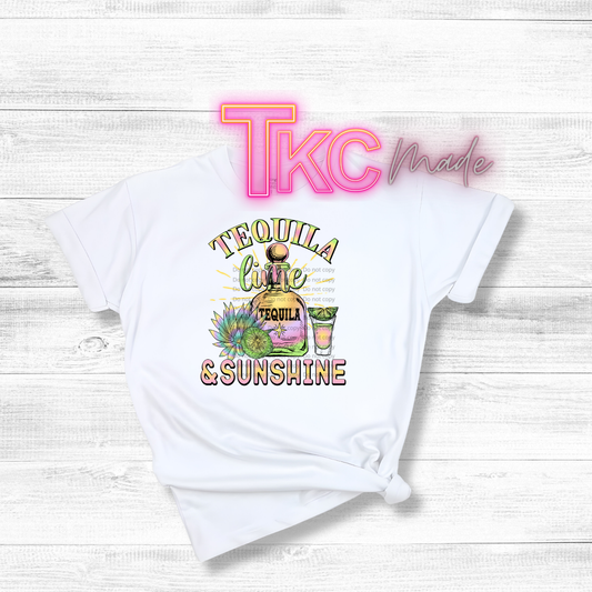 White t-shirt with 'Tequila Lime & Sunshine' graphic and 'TLC Made' branding on a light wooden background.