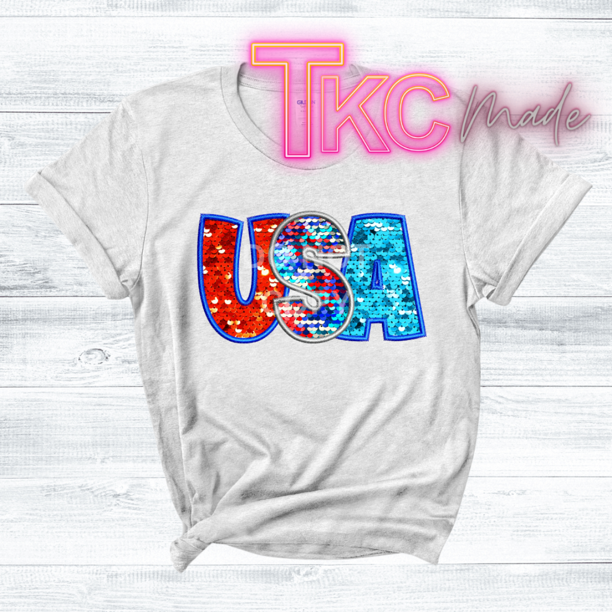 White t-shirt with colorful 'USA' design and 'TKC Made' text on a white background