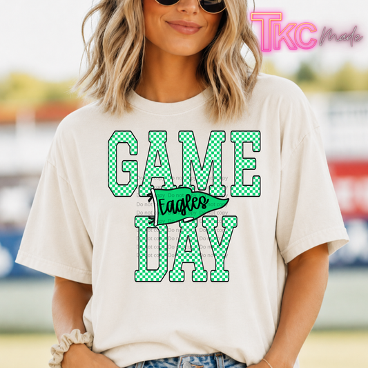A woman wearing a cream-colored graphic t-shirt with 'GAME DAY' in green-and-white checkered letters and a green pennant reading 'Eagles'.