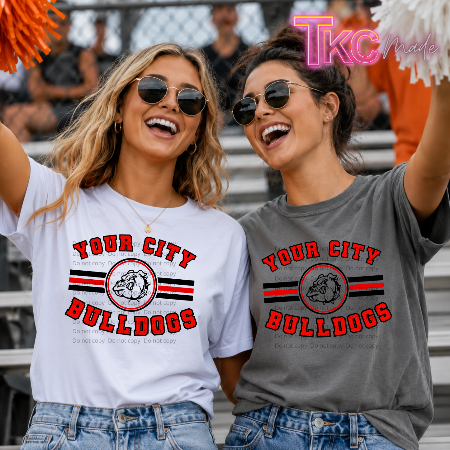 Two women in a stadium wearing custom printed athletic t-shirts. The woman on the left wears a white t-shirt with red and black text reading 'YOUR CITY BULLDOGS' and a bulldog graphic.