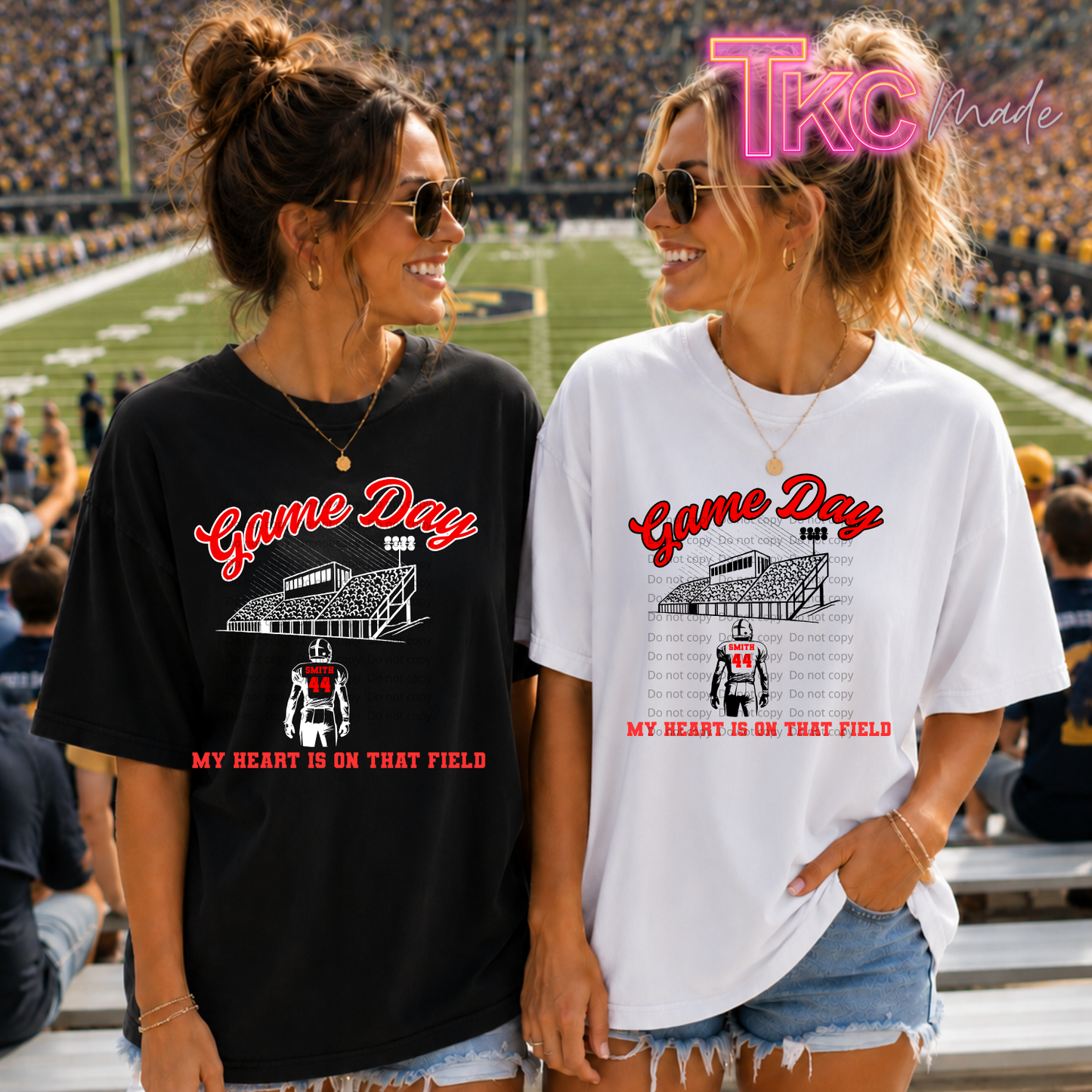 Two women standing in a stadium wearing oversized 'Game Day' graphic T-shirts, one black and one white, with a 'TKO Made' watermark in the top right.