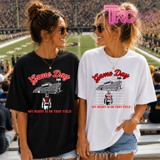 Two women standing in a stadium wearing oversized 'Game Day' graphic T-shirts, one black and one white, with a 'TKO Made' watermark in the top right.