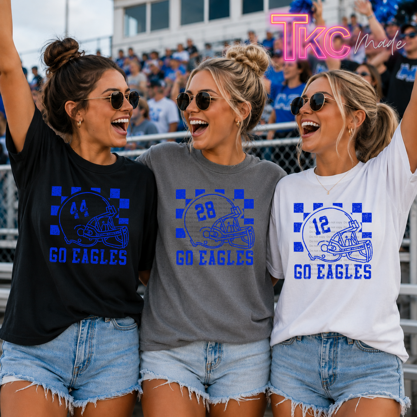Three women wearing matching graphic t-shirts with blue and white 'GO EAGLES' football helmet designs, standing together in stadium bleachers. The shirts are shown in black, gray, and white colorways, with a 'Tkc Made' watermark in the top right corner.