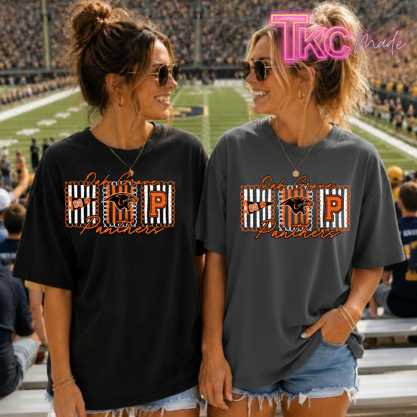 Two women standing in a stadium wearing matching graphic T-shirts. The shirt design features a large block letter 'P' with a stripe pattern, the letters 'OG', and the words 'Oak Grove Panthers' in orange script.